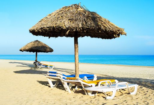 Beach chair under rustic umbrellas in a deserted beach