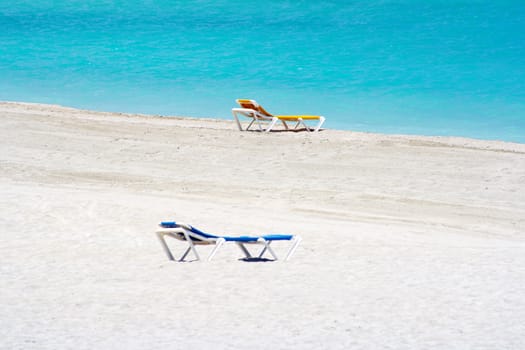 Yellow and blue beach chairs in the sand