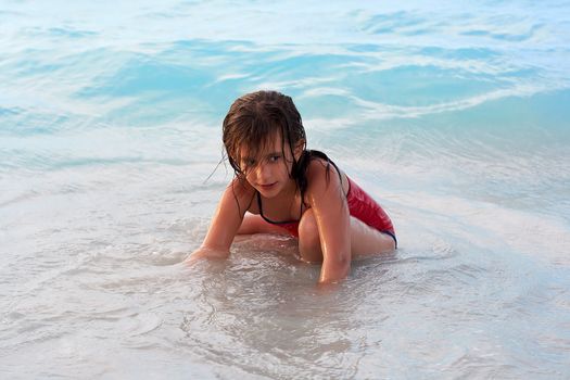 Beautiful caucasian girl sitting in the beach with a mischievous look