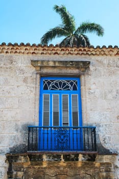 Old balcony with a palm tree in the background in Havana