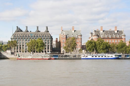 Ancient houses across the river Thames in London with boats in the foreground