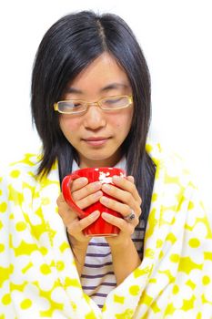 Chinese woman sitting under a blanket with a cup of tea