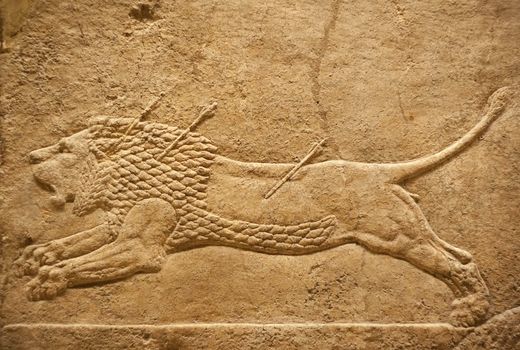 Old assyrian relief of a lion beig hunted with arrows