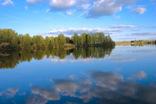 Sky reflexion in a pond surrounded with trees removed in the autumn afternoon