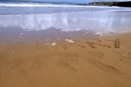 kerry inscribed on the beach with ocean waves and a cliffs in the background
