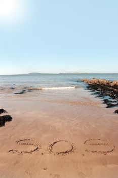 sos inscribed on the beach with waves in the background on a hot sunny day
