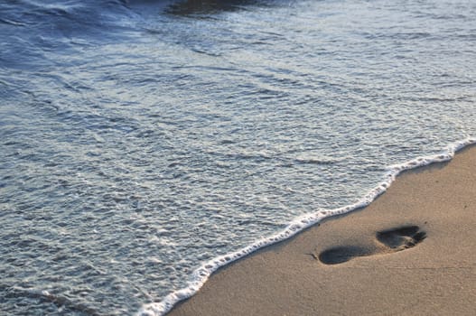 Footprint on the sandy beach and sea wave