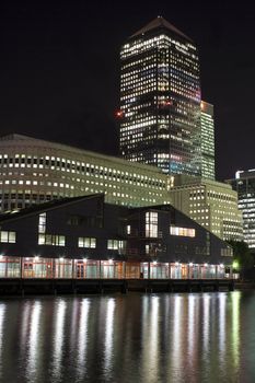 Canary Wharf skyscrapers in London at night with reflections in the river