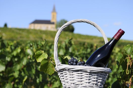 Bottle of red wine in a basket of reasons near a typical church