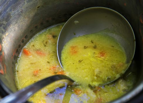 Pig-iron saucepan with vegetable soup and a scoop