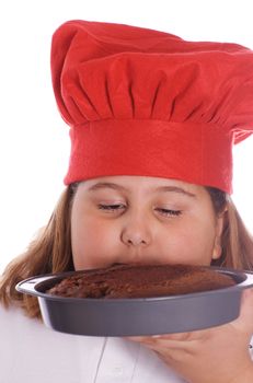A young girl holding up a brown cake that she baked, isolated against a white background