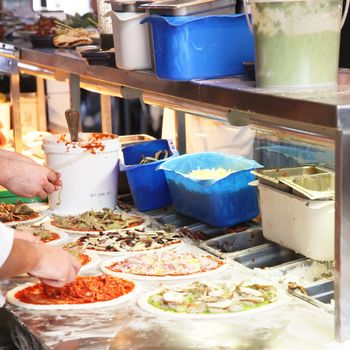 Different Pizzas Being Made in a Kitchen