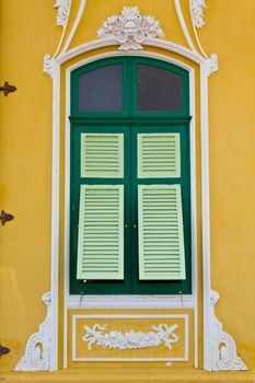 the closed green window on the yellow wall