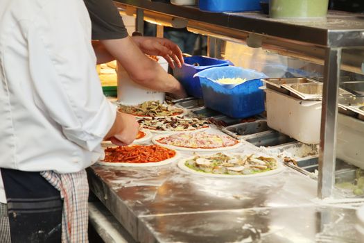 Different Pizza Being Made in a Kitchen