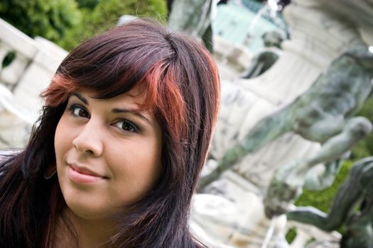 A young Spanish model outdoors in front of an old fountain.