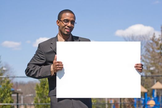 A young man holds up a blank white sign with copyspace.