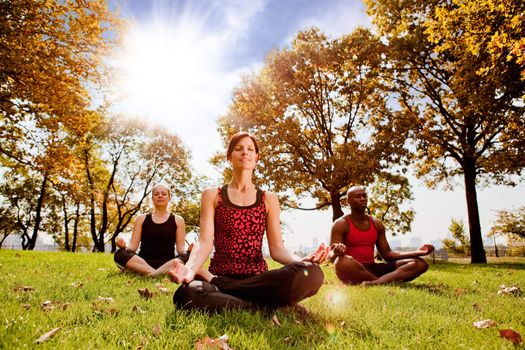 A group of people meditation in a city park in the morning - taken into the sun with lens flare