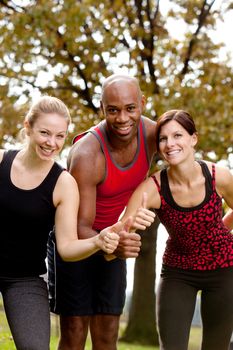 A group of people exercising in the park, giving a thumbs up to the camera