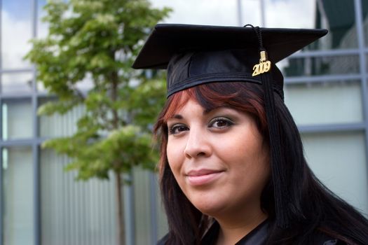 A recent graduate posing in her cap and gown.