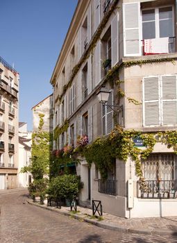 Old Parisian street with blossoms and cobbled road in suburb of Montmartre