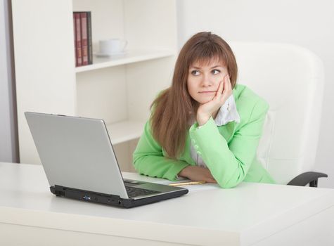 Young businesswoman sits on a workplace and misses