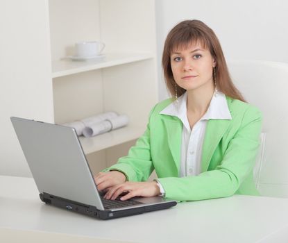 The young beautiful woman works at office with the computer