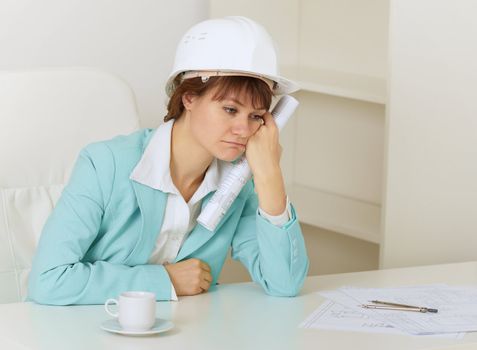 The woman the engineer sits on a workplace at office and mourns