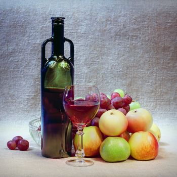 Art still-life from wine, grapes and apples against a sacking