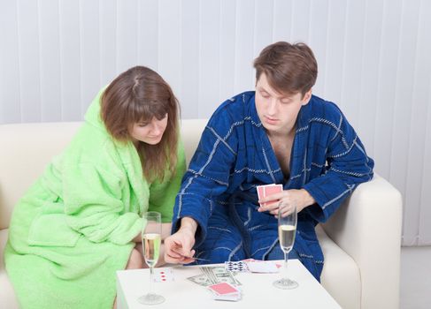 The guy and the girl play cards on money at home
