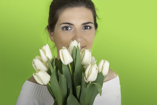 Beautiful woman on a green background with white tulips on the hands