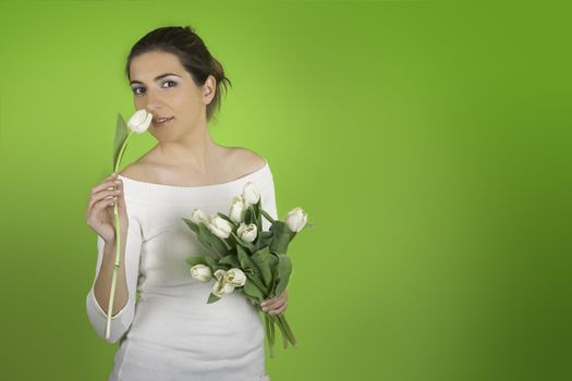 Beautiful woman on a green background smeeling a tulip