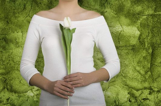 Woman with white tulips on is hands on a green wall