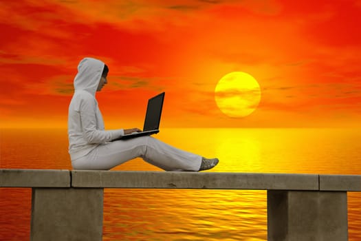 Woman working with is laptop at the sunset