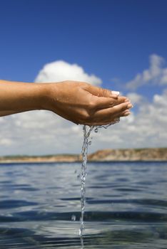 Close up of woman hands catching water from the ocean