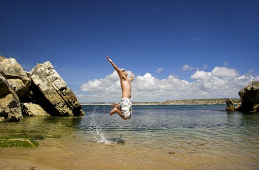 Young man full of energy jumping on the beach