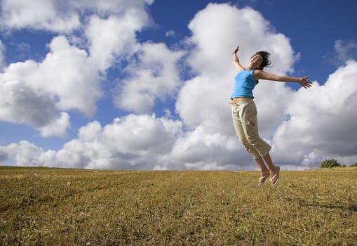 Beautiful woman jumping on a golden meadow