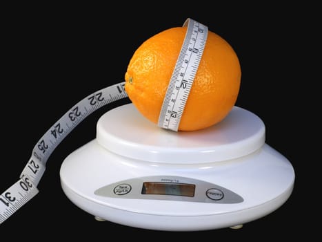 Orange with tape measure on white scale isolated on black background