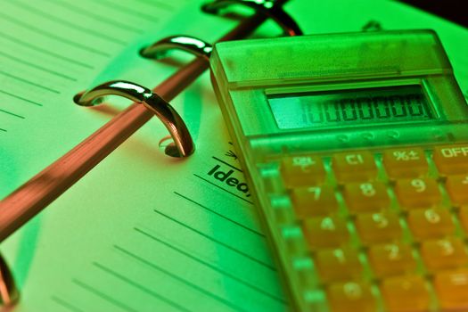 business series: note book and calculator in a green light