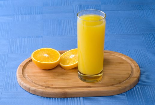 The orange cut with segments and juice glass on a table covered with a cloth.