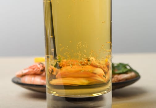 The plate with shrimps is visible through a glass with beer.