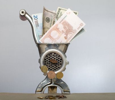 Denominations dollars and euro in an old metal meat grinder.