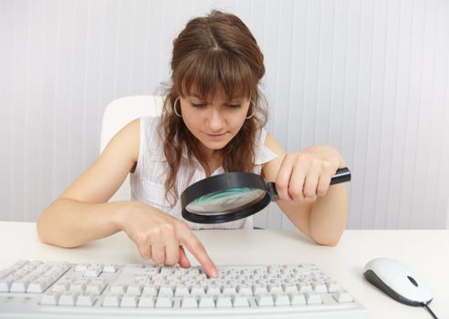 The girl with a poor eyesight works on the keyboard by means of a magnifier
