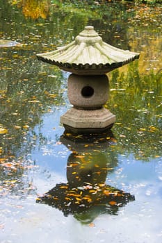 Chinese garden in autumn wirh lantern and reflection in pond 