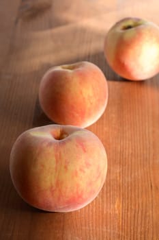 Three freshness peach fruits lying on wooden surface