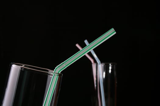 Glass with straw for cocktails on a black background. On a background the glass image is washed away for volume.