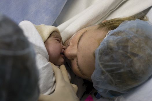 New born baby girl kissing her mother for the first time