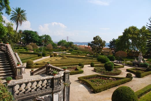 beautiful ornamental Ajuda garden with April 25th bridge on background in Lisbon, Portugal