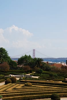 beautiful ornamental Ajuda garden with April 25th bridge on background in Lisbon, Portugal