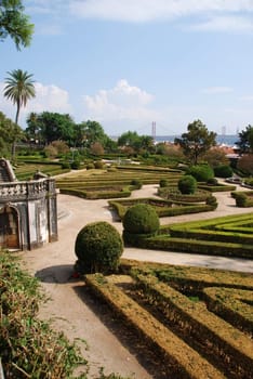 beautiful ornamental Ajuda garden with April 25th bridge on background in Lisbon, Portugal