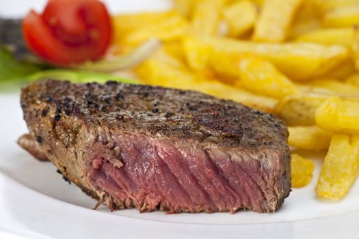 closeup of a beef steak with french fries on a white background